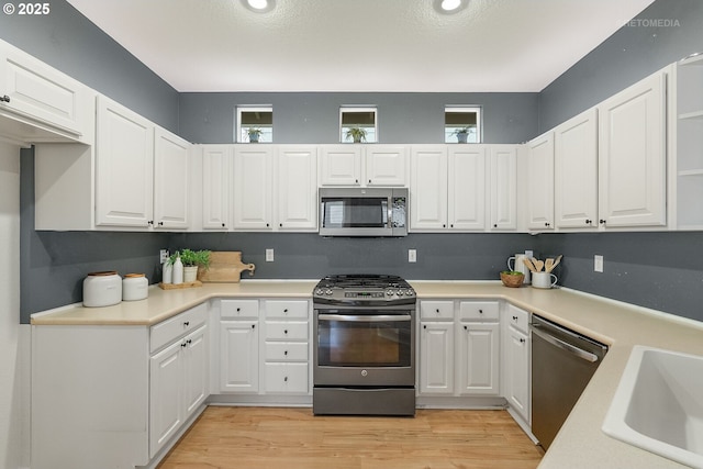 kitchen with a wealth of natural light, white cabinets, stainless steel appliances, and a sink