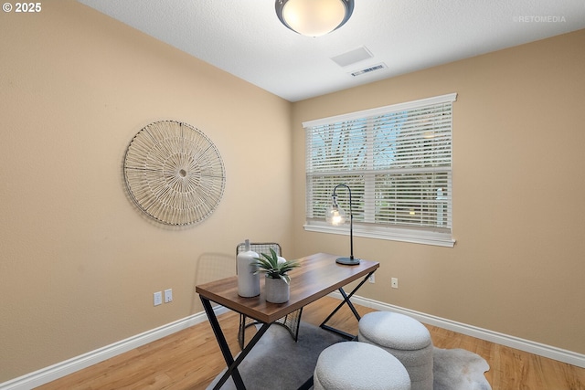 office space with light wood-style flooring, visible vents, and baseboards