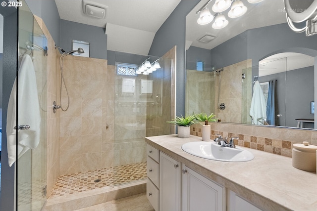 bathroom featuring tasteful backsplash, vanity, and a tile shower