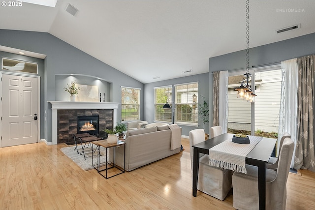 living room with visible vents, vaulted ceiling, a fireplace, and light wood finished floors