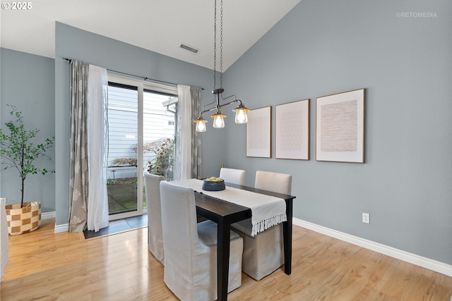 dining room with visible vents, baseboards, light wood-type flooring, and lofted ceiling