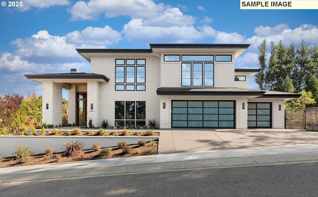 contemporary home featuring driveway, an attached garage, fence, and stucco siding