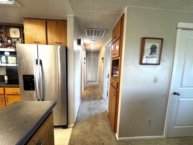 corridor with visible vents, a textured ceiling, baseboards, and light carpet