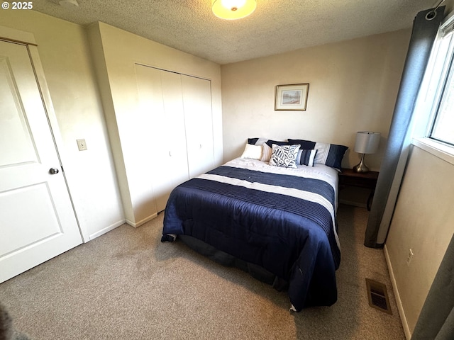 carpeted bedroom featuring baseboards, a closet, a textured ceiling, and visible vents