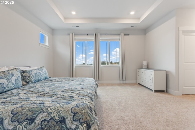 bedroom featuring light colored carpet and a tray ceiling