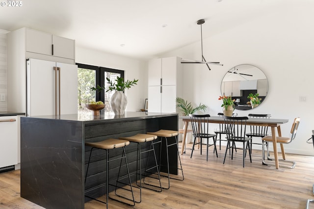 kitchen featuring dark countertops, white appliances, light wood-type flooring, and white cabinetry