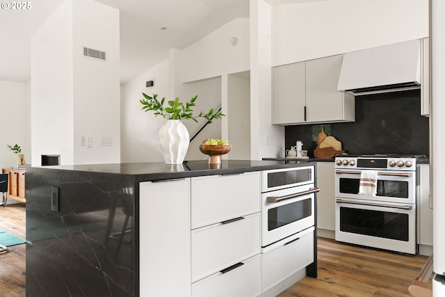 kitchen featuring white appliances, visible vents, dark countertops, wood finished floors, and custom exhaust hood