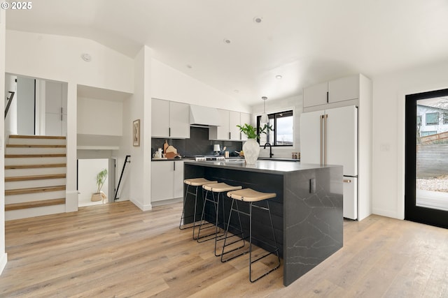 kitchen with lofted ceiling, a center island, a kitchen bar, and freestanding refrigerator