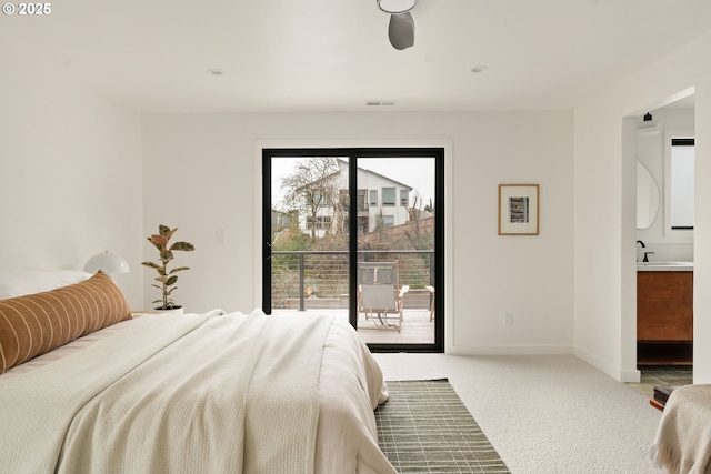 carpeted bedroom featuring ensuite bathroom, a sink, visible vents, baseboards, and access to outside