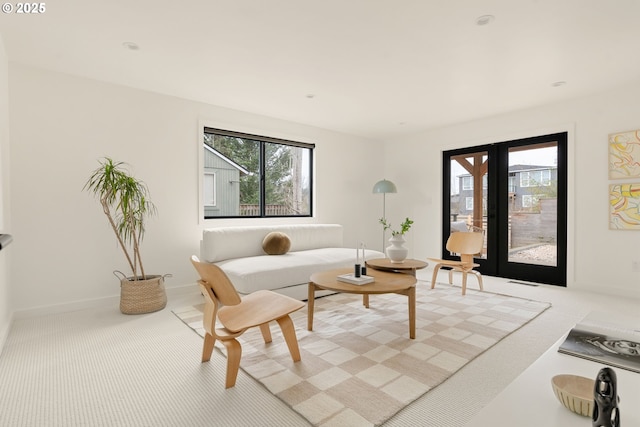 living area with french doors, light carpet, and baseboards