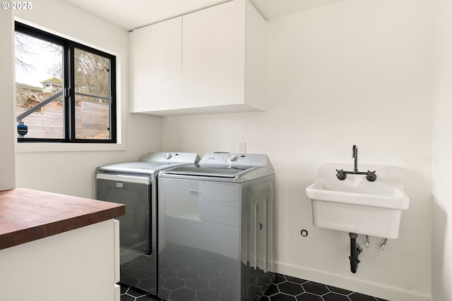 laundry area featuring baseboards, cabinet space, a sink, and washing machine and clothes dryer