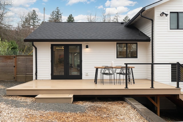 rear view of house with a shingled roof, outdoor dining space, fence, and a wooden deck