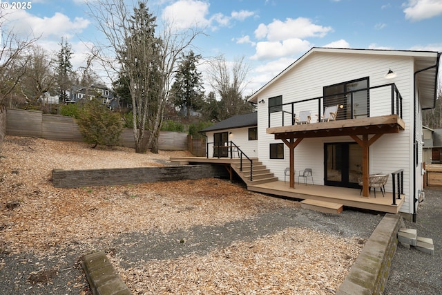 rear view of property featuring a fenced backyard, a balcony, and a wooden deck