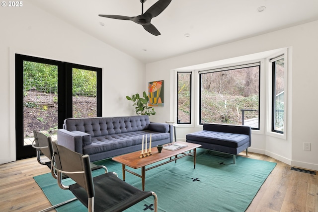 living area featuring vaulted ceiling, a wealth of natural light, light wood finished floors, and visible vents