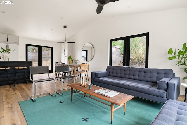 living area featuring ceiling fan, light wood-type flooring, lofted ceiling, and a wealth of natural light