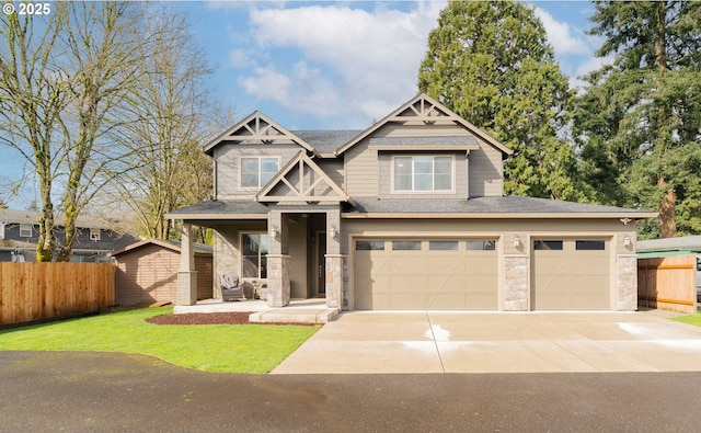 craftsman inspired home featuring fence, roof with shingles, an attached garage, concrete driveway, and stone siding