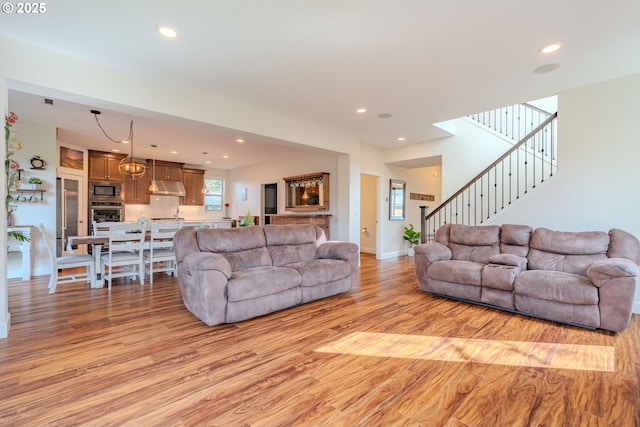 living room with recessed lighting, light wood-style flooring, and stairs