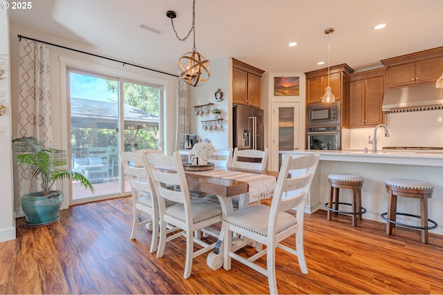 dining room featuring recessed lighting, light wood-type flooring, an inviting chandelier, and visible vents