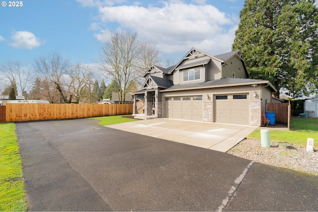 view of front of home featuring a garage, fence, stone siding, and driveway