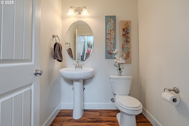 bathroom featuring a sink, toilet, baseboards, and wood finished floors