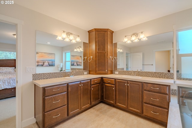 bathroom with double vanity, connected bathroom, and a sink