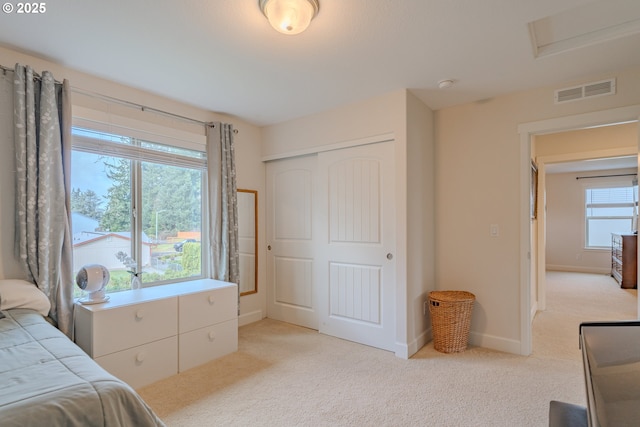 bedroom featuring light carpet, visible vents, baseboards, and a closet