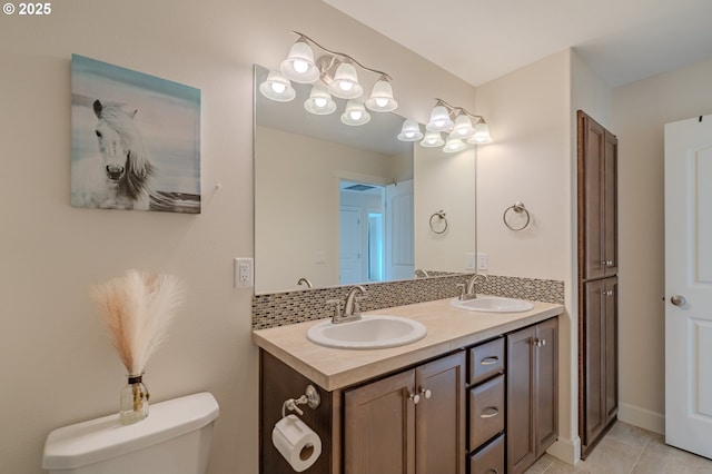 bathroom with decorative backsplash, double vanity, toilet, and a sink