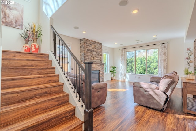 living area with a fireplace, stairs, baseboards, and wood finished floors