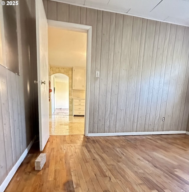 unfurnished room featuring light wood-type flooring and wood walls