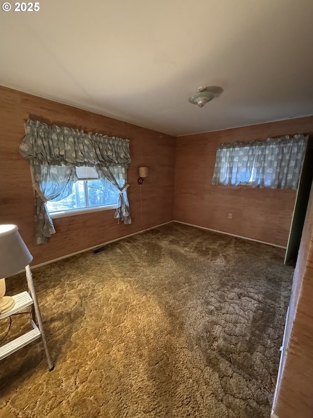 carpeted spare room featuring wood walls