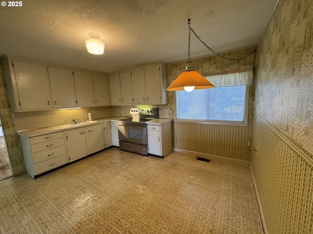 kitchen featuring white cabinets, sink, stainless steel electric range oven, a textured ceiling, and decorative light fixtures