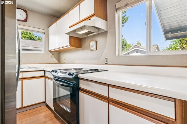 5246 SE 65th Ave, Portland, OR 97206 - kitchen with black range with electric cooktop, freestanding refrigerator, under cabinet range hood, white cabinets, and light countertops
