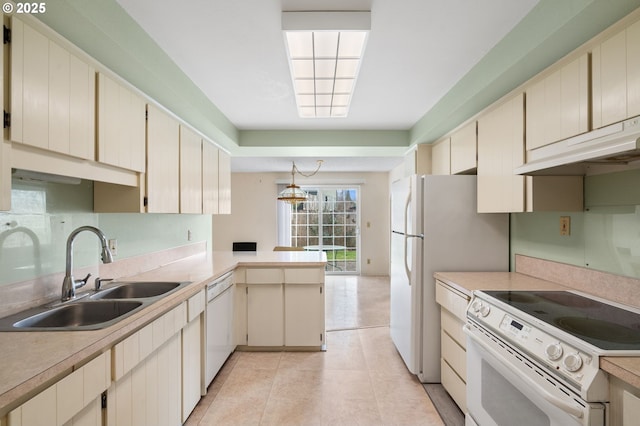 kitchen featuring pendant lighting, white appliances, cream cabinets, and sink