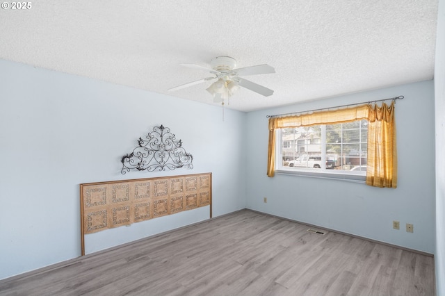 unfurnished bedroom with ceiling fan, a textured ceiling, and light wood-type flooring