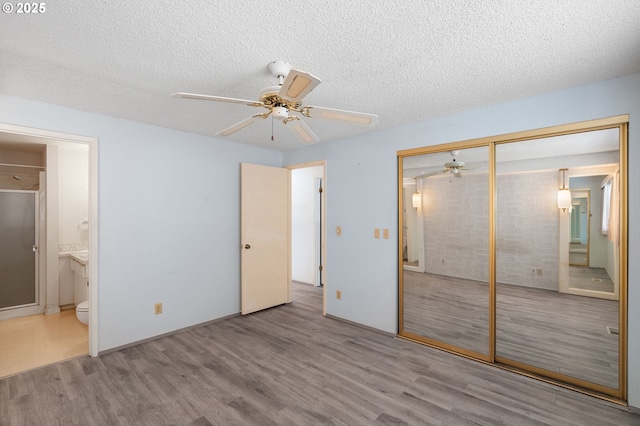 unfurnished bedroom featuring ensuite bath, light hardwood / wood-style flooring, a closet, and a textured ceiling