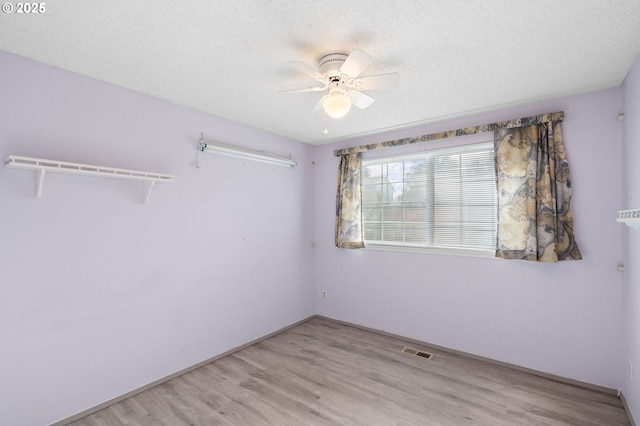 empty room featuring ceiling fan, light hardwood / wood-style flooring, and a textured ceiling