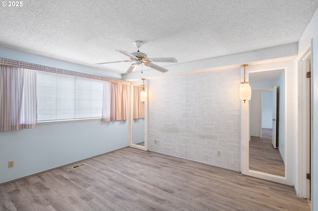 unfurnished room featuring ceiling fan, hardwood / wood-style floors, and a textured ceiling