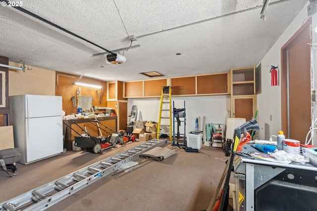 garage with a garage door opener, white fridge, and a workshop area