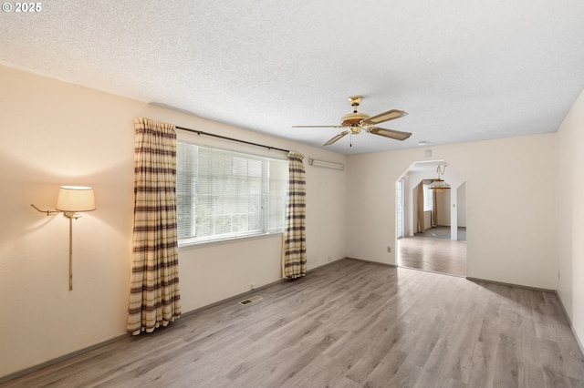 empty room with ceiling fan, light hardwood / wood-style flooring, and a textured ceiling