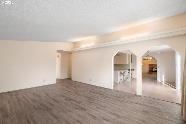 unfurnished room featuring hardwood / wood-style floors, a fireplace, and a textured ceiling