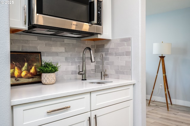 10014 NE 146th Ave, Vancouver, WA 98682 - kitchen with stainless steel microwave, white cabinetry, decorative backsplash, light wood-type flooring, and light countertops
