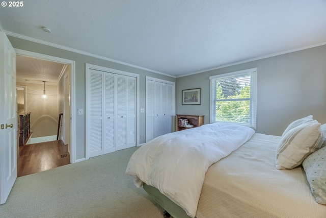 carpeted bedroom featuring crown molding, multiple closets, and baseboards