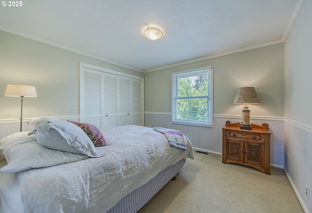 carpeted bedroom featuring wainscoting, ornamental molding, and a closet