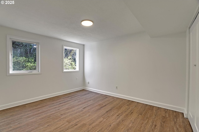 spare room featuring baseboards and wood finished floors