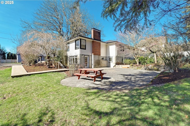 back of house featuring fence, a yard, a chimney, and a patio