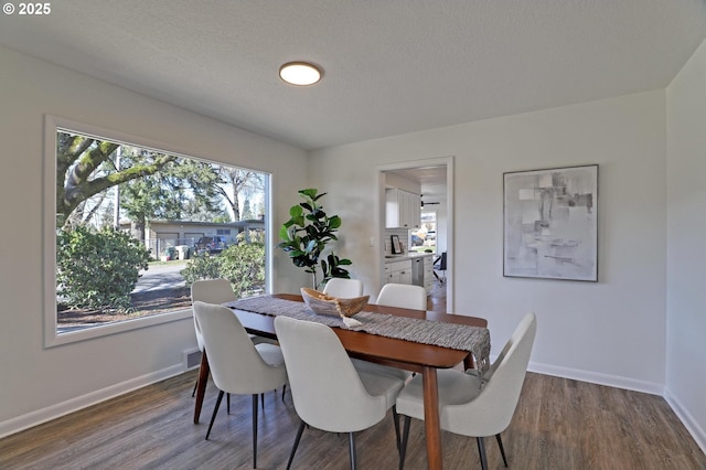 dining area featuring a textured ceiling, baseboards, and wood finished floors