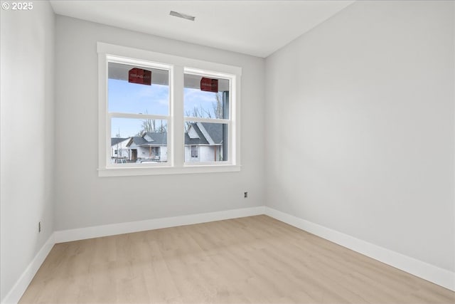 spare room featuring baseboards and wood finished floors