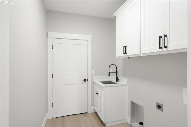 clothes washing area featuring cabinet space, baseboards, light wood-style flooring, electric dryer hookup, and a sink