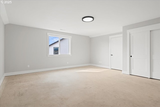 unfurnished bedroom with concrete floors, baseboards, and vaulted ceiling