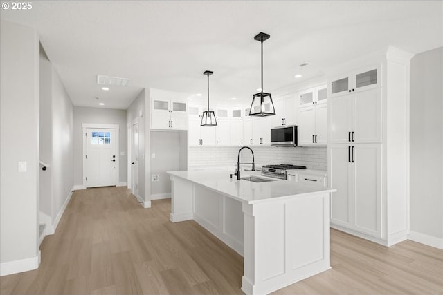 kitchen featuring stainless steel appliances, a sink, visible vents, light countertops, and light wood finished floors